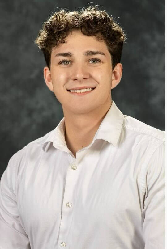 Evan Jackson smiling with a white button-up shirt on.
